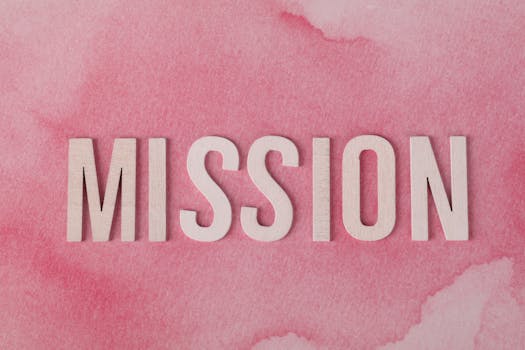 Wooden letters spelling 'MISSION' on a soft pink watercolor background.